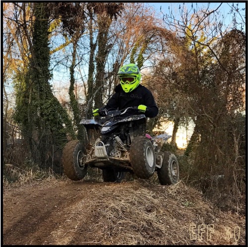 Riding an ATV over a tabletop on a dirt trail.
